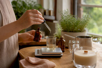 Hands measuring fragrance oil for candle making