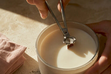 Hands trimming a wooden candle wick